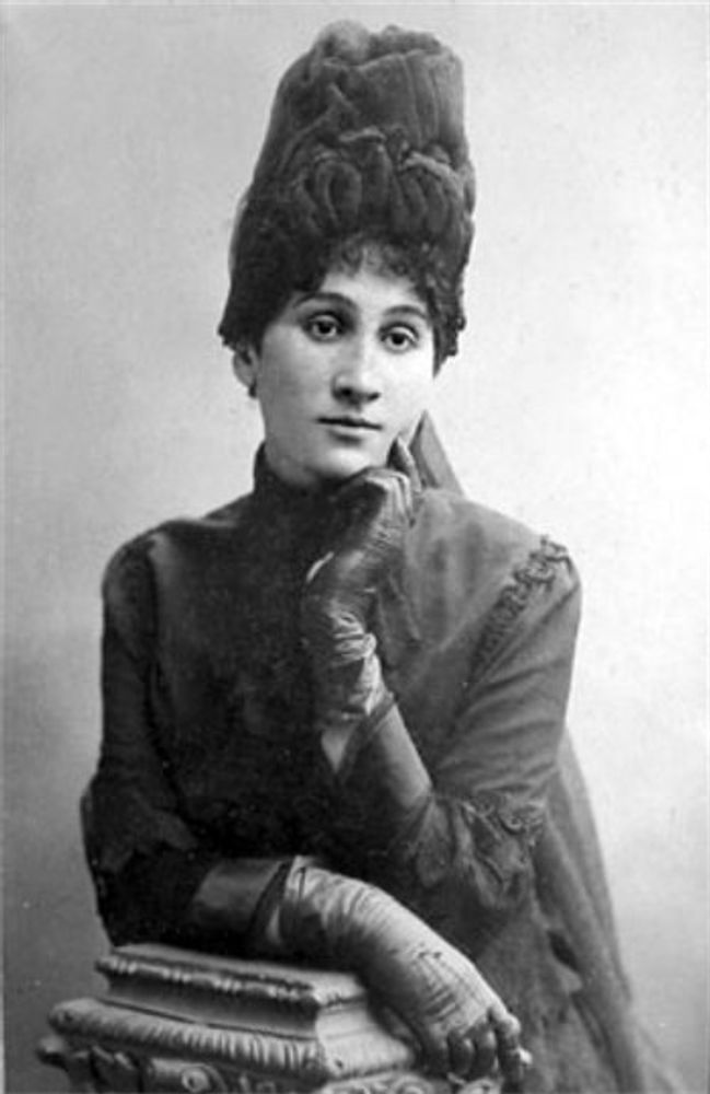 Maria Zankovetska, photo before 1917. Black and white. She is wearing a hat and some sort of veil is partially visible. She is also wearing gloves and a dress with turtle neck.