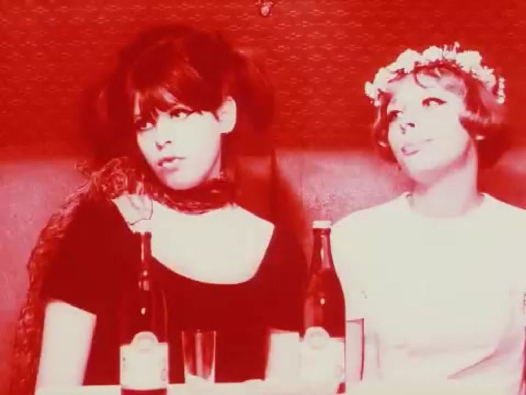 Two women are on a table with two bottles in front of each of them.