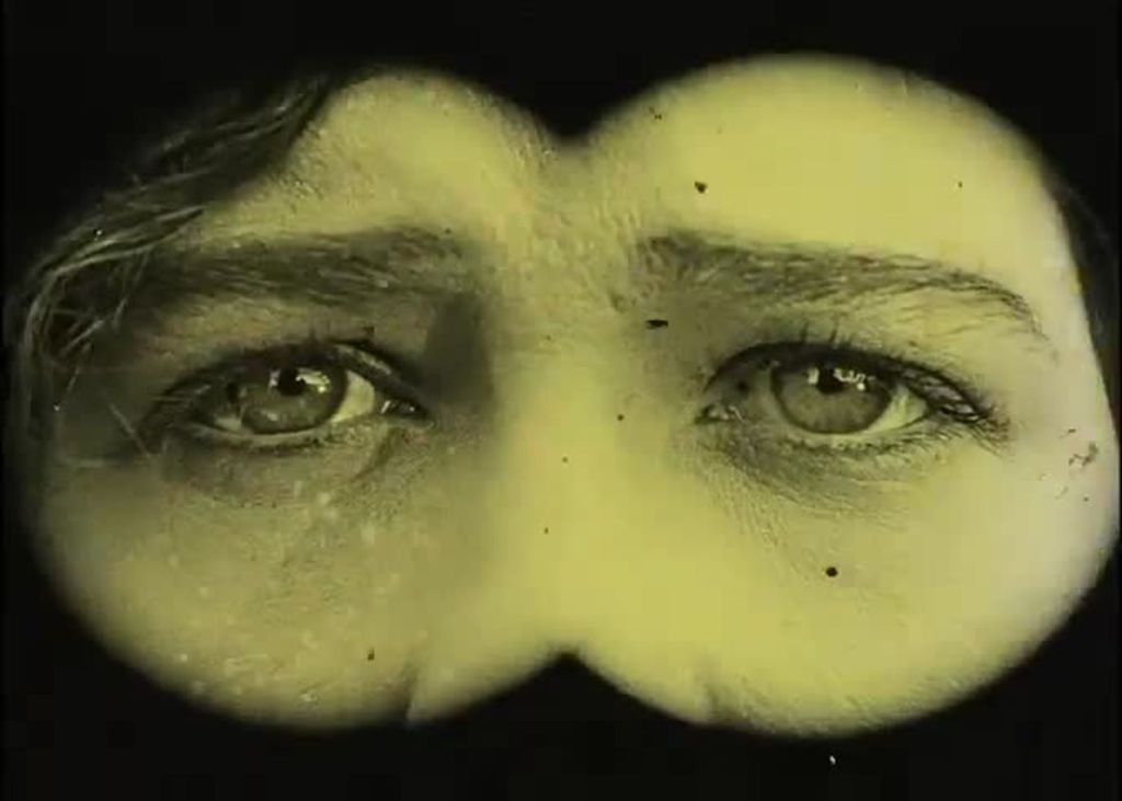 We can see the eyes of a woman through a hole. A small part of her hair and nose are also visible.